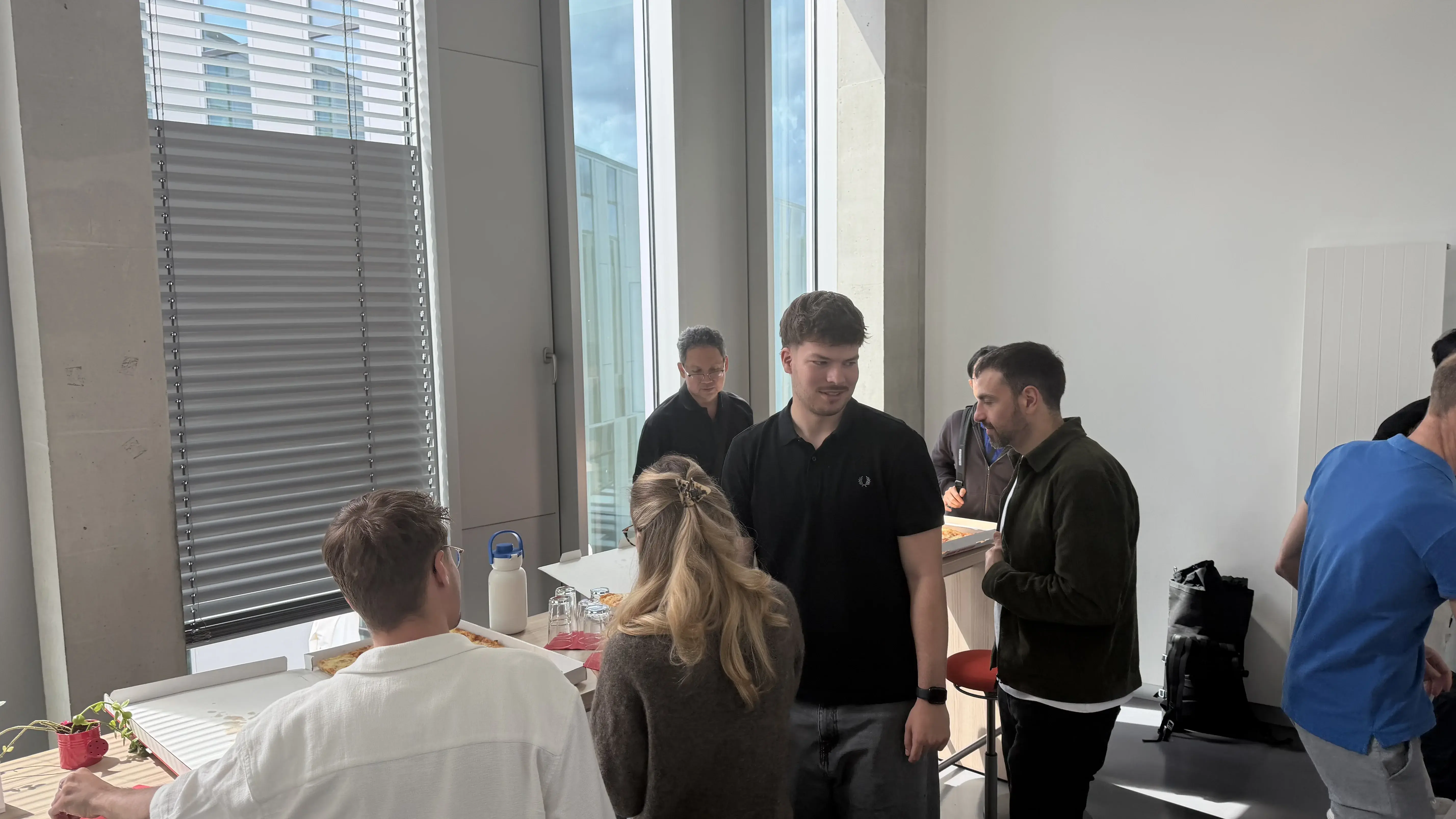 Studierende sitzen in der Küche und essen gemeinsam Pizza