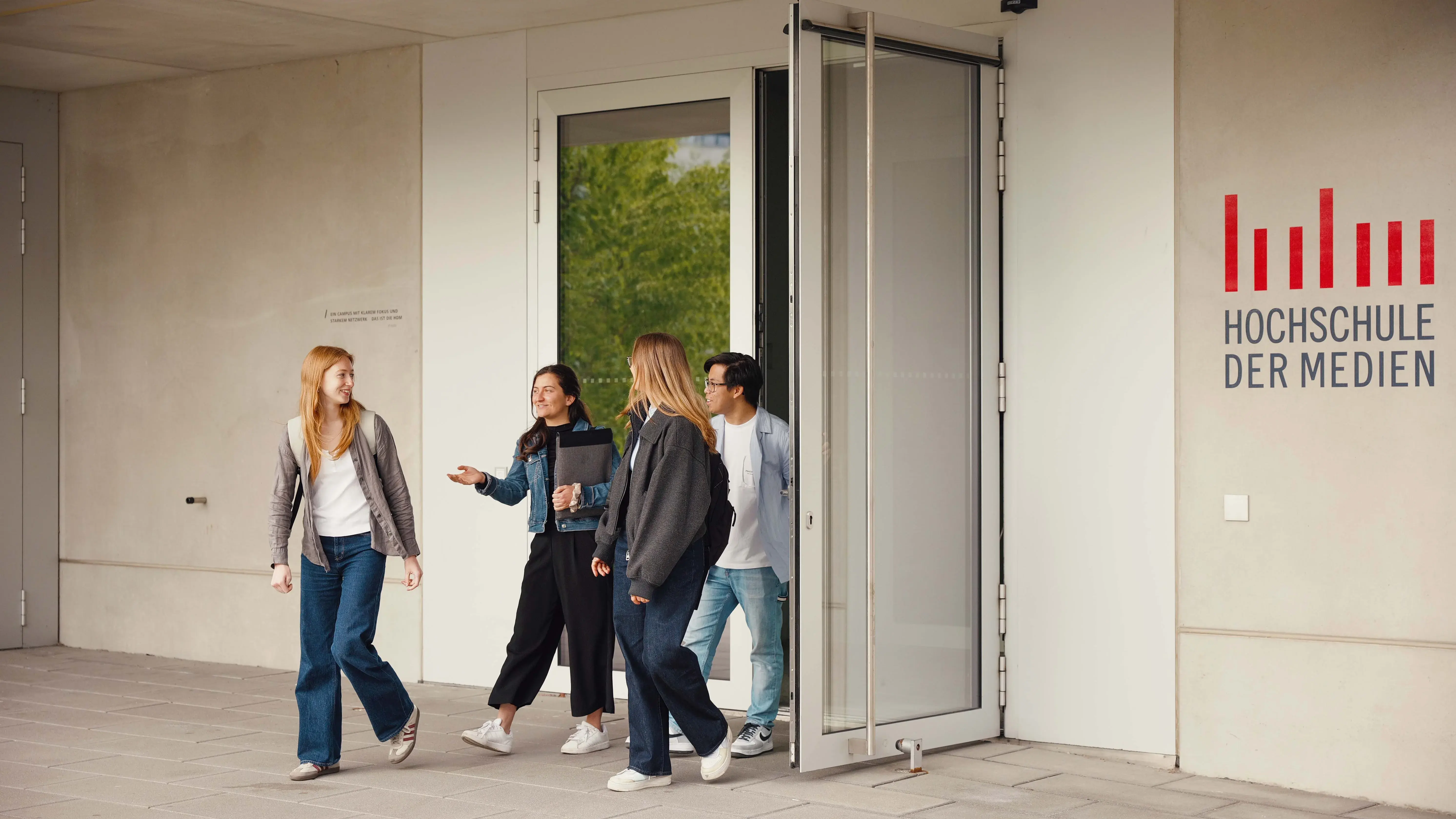 Studierende unterhalten sich beim Verlassen der Hochschule der Medien.