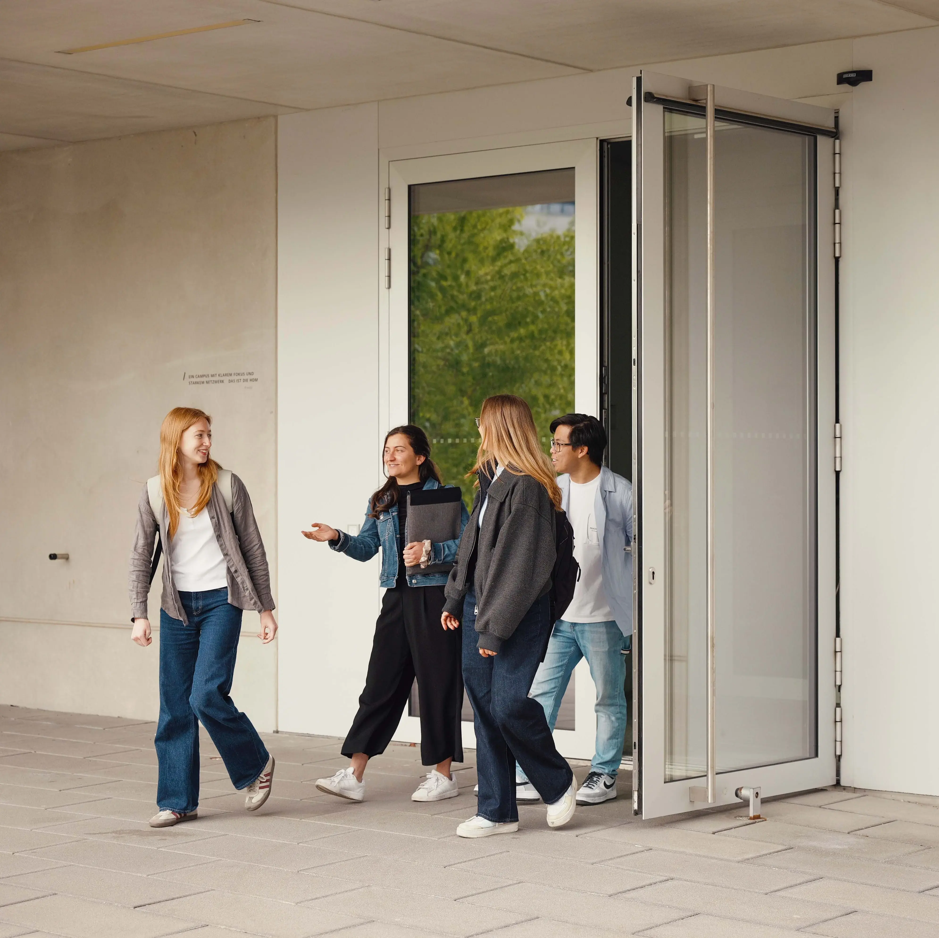Studierende unterhalten sich beim Verlassen der Hochschule der Medien.
