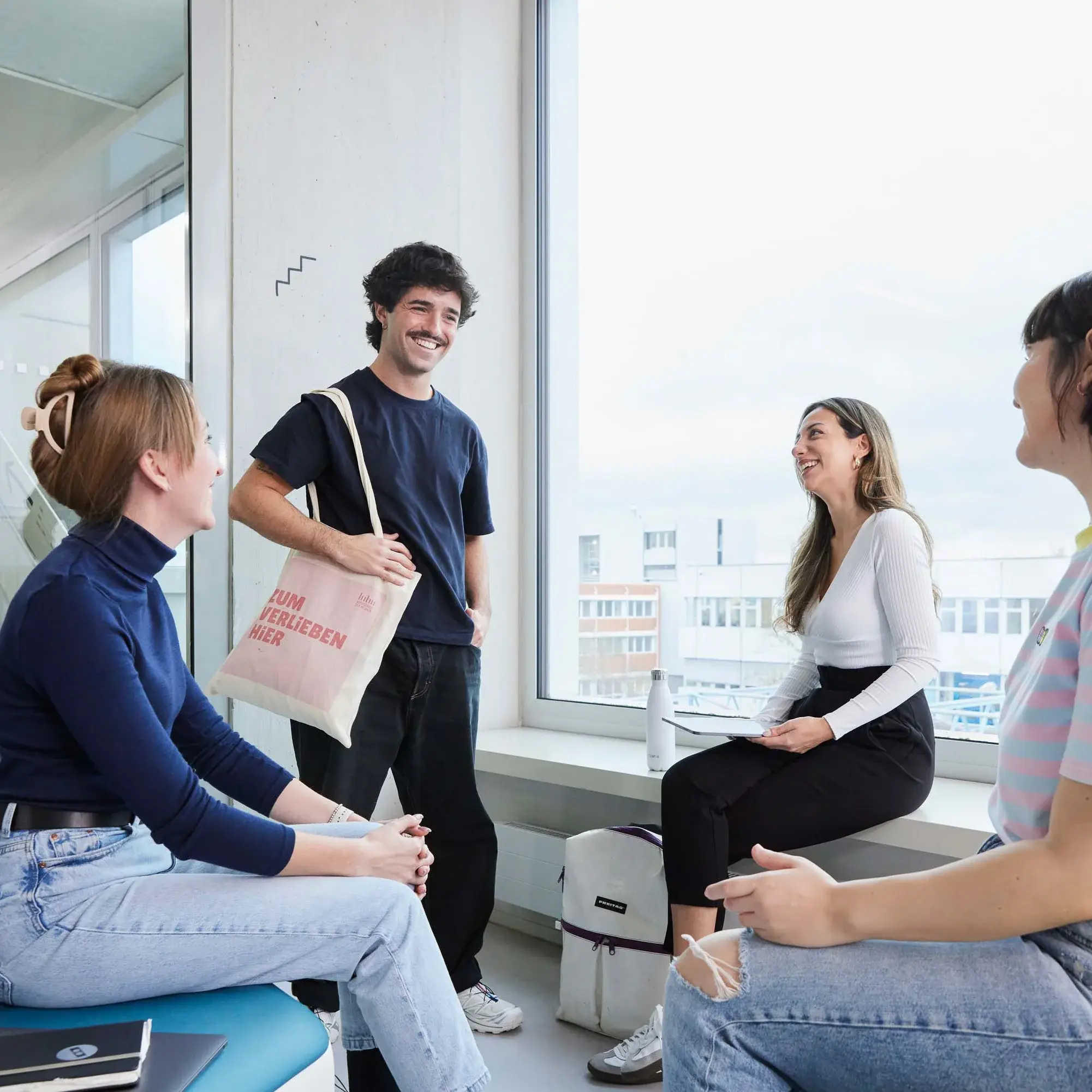 Studierendengruppe aus vier Personen trifft sich innerhalb eines Gebäudes.