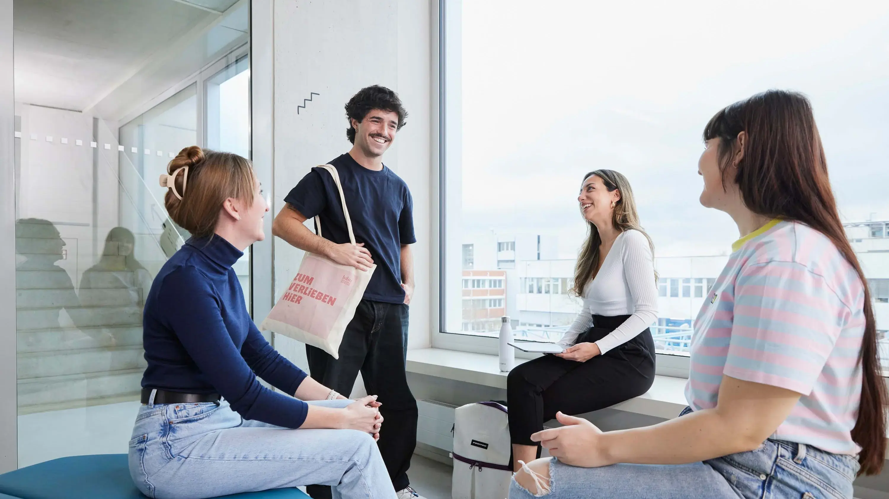 Studierendengruppe aus vier Personen trifft sich innerhalb eines Gebäudes.